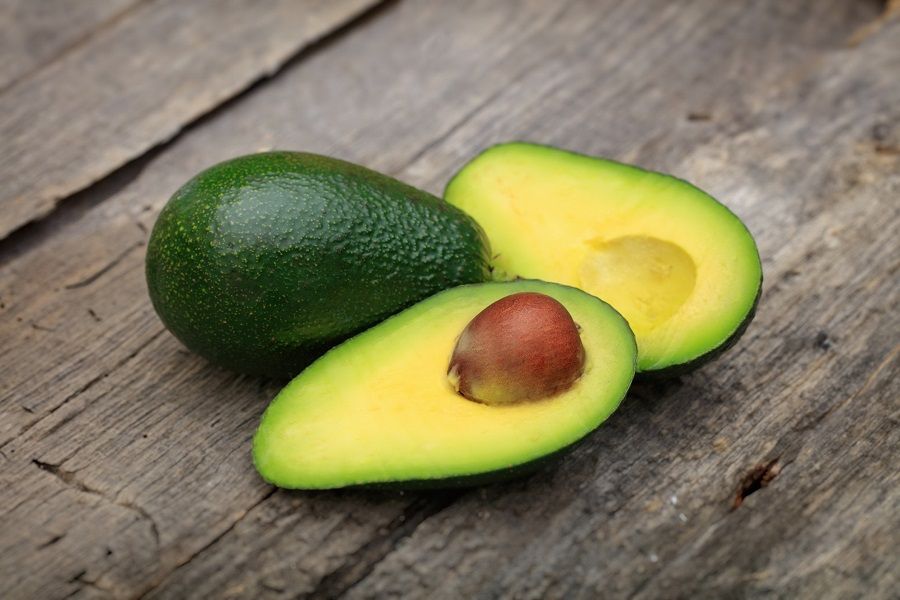55867734 - two avocados one cut in two with seed, on wooden surface