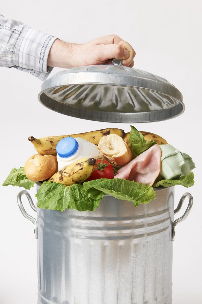 49370185 – hand putting lid on garbage can full of waste food