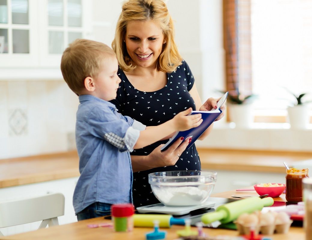 Smart cute child helping mother in kitchen