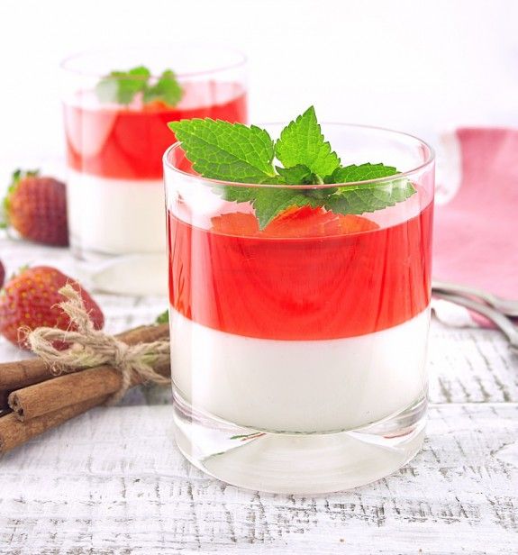 Panna cotta dessert with strawberry jelly on rustic wooden backg