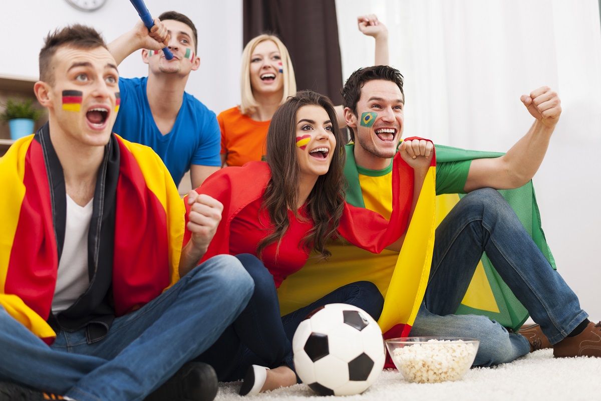 Group of multinational people cheering football match at home