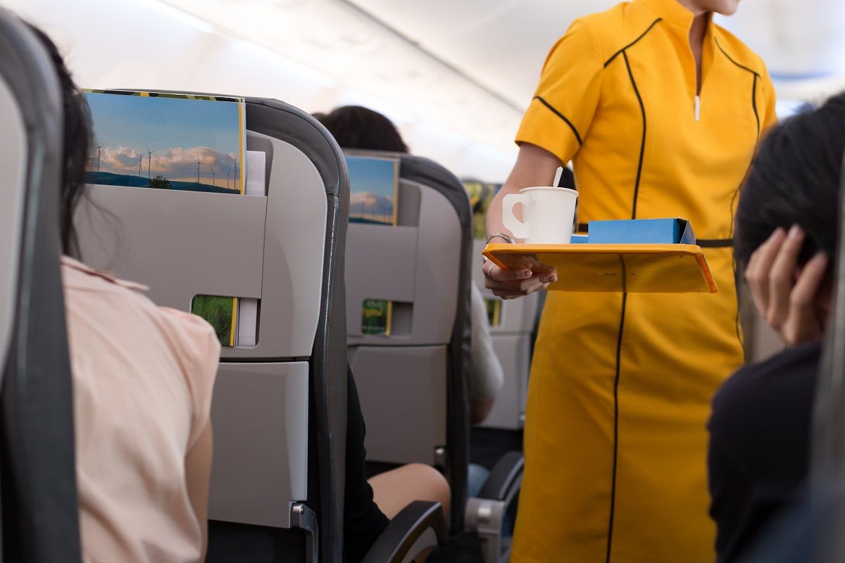 Flight attendant offering beverage to a passenger