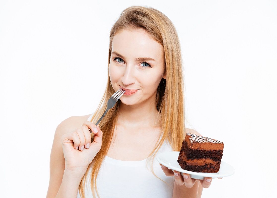 Attractive smiling young woman eating piece of chocolate cake