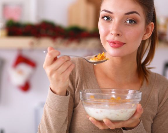 Smiling attractive woman having breakfast in kitchen interior