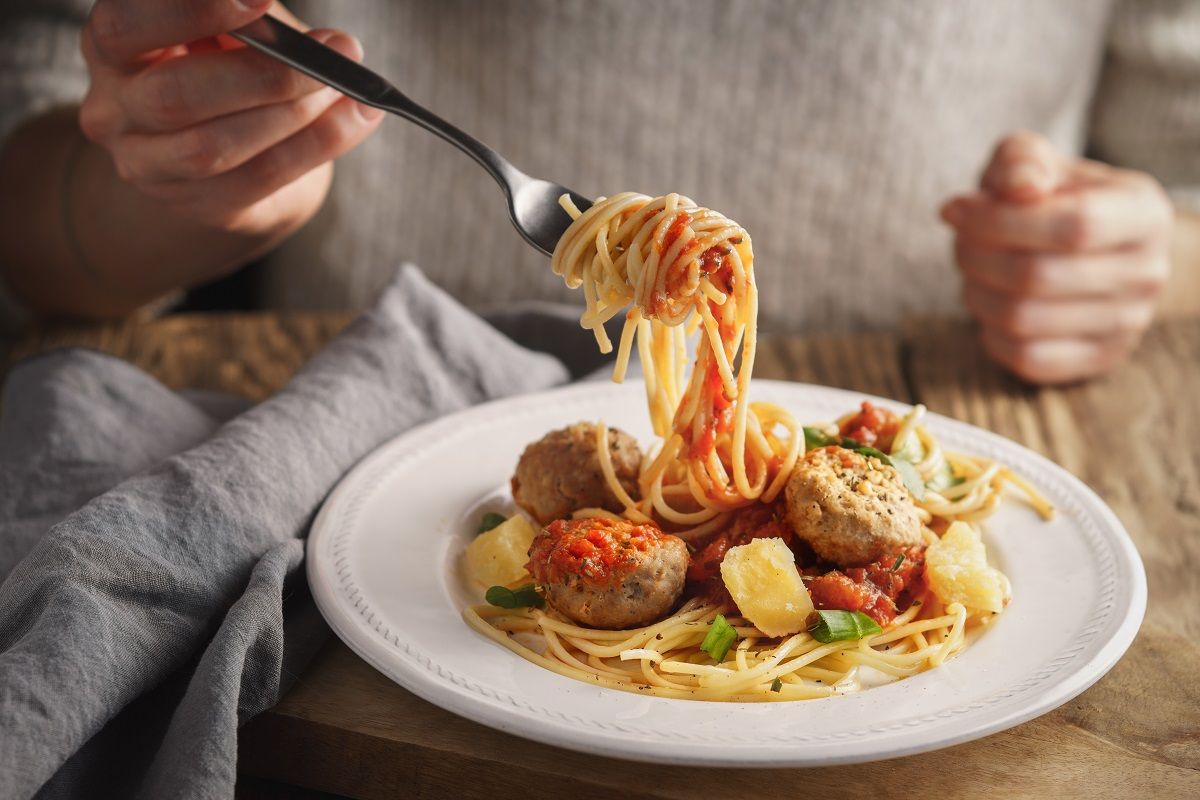 Woman eating spaghetti with meatballs and cheese