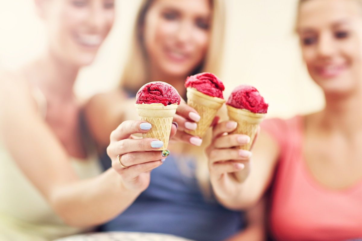 Three beautiful young women eating ice-cream at home