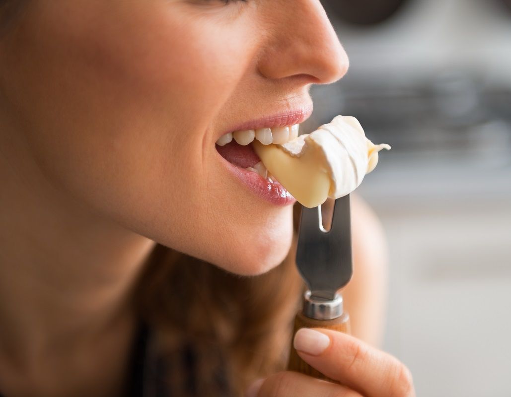 Closeup on young woman eating camembert