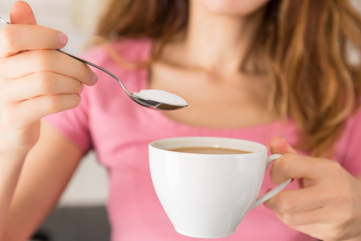 Woman adding a spoonful sugar to her coffee