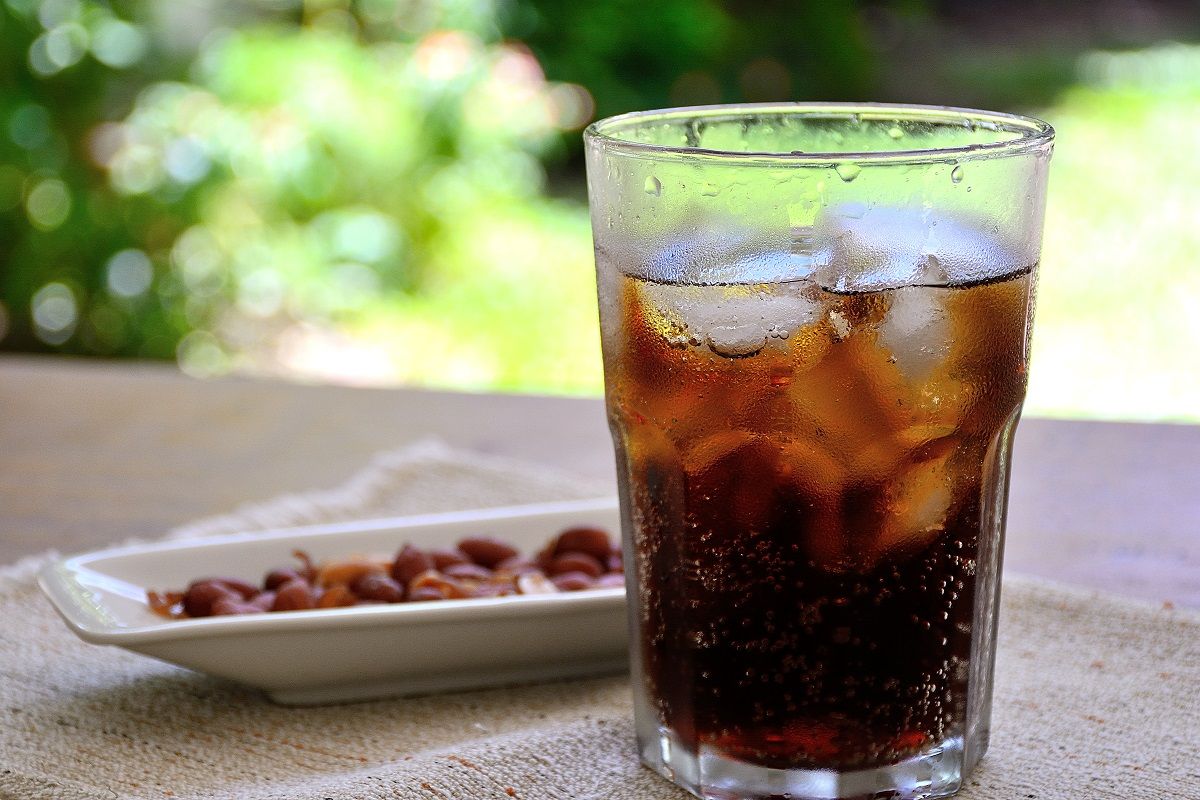 65988925 – fresh cola in a glass with a snak of peanuts on a wood table