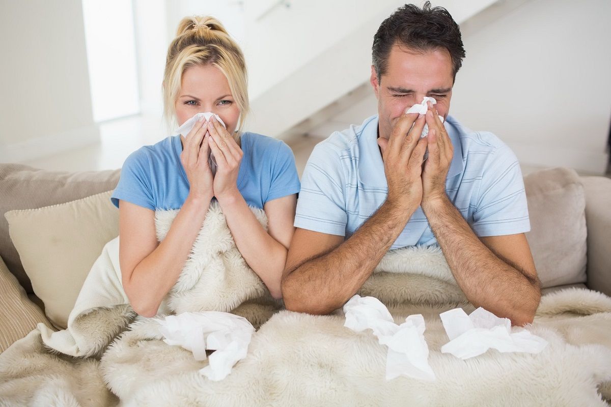 27150222 – couple suffering from cold as they sit on bed at home