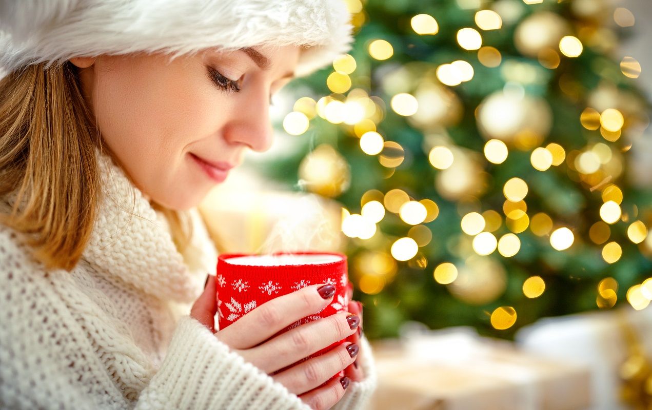 happy woman with a mug of tea near Christmas tree