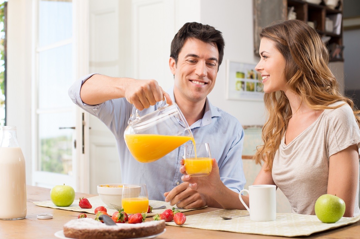 20837953 – portrait of happy man pouring juice in glass for young woman