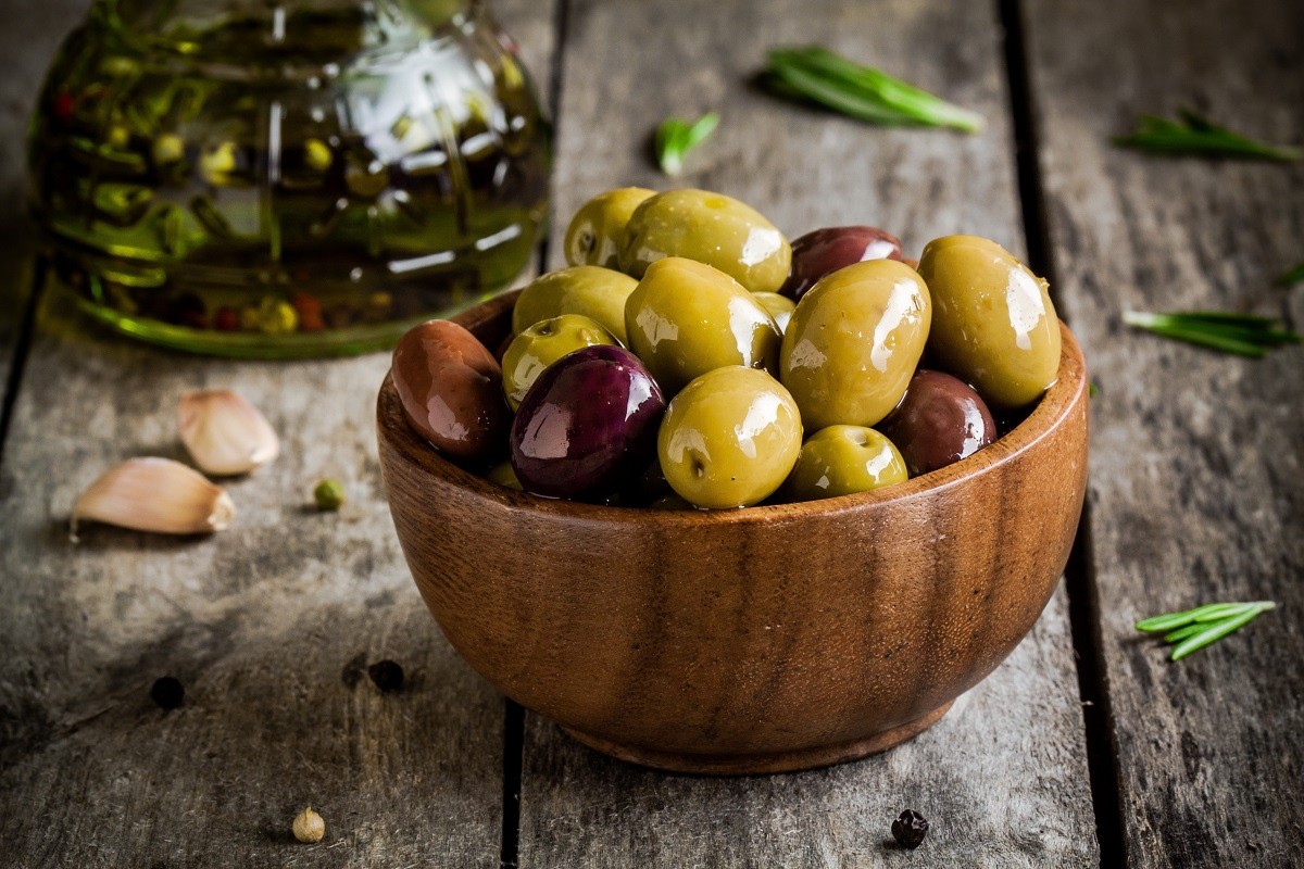 mixed olives in a bowl with rosemary, olive oil and garlic on a