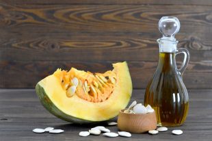 Pumpkin seed oil and pumpkin slice on wooden background