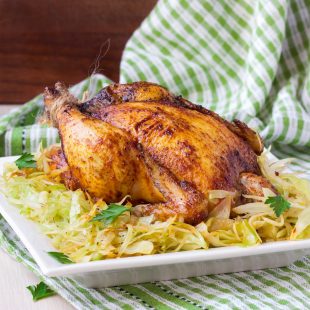 Roasted whole chicken with golden crust and garnish of stewed ca