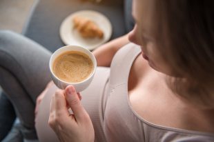Calm pregnant woman drinking coffee at home