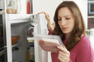 Concerned Woman Looking At Pre Packaged Meat