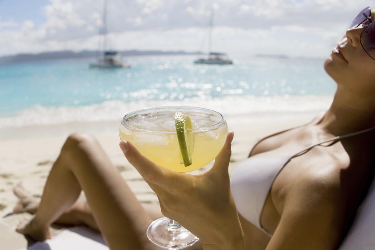 woman relaxing at the beach drinking margarita cocktail