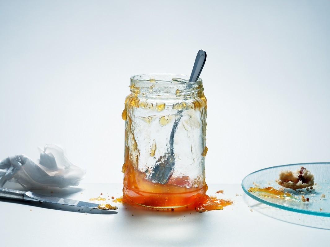 Messy, almost empty jar of homemade apricot preserves with spoon