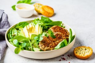 Green salad with avocado, cucumber and lentil patties in white p