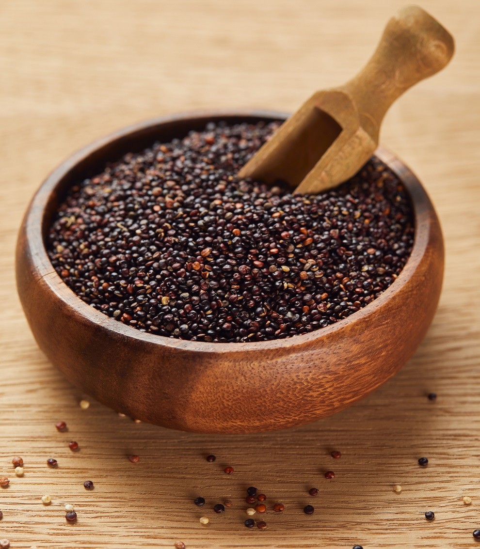 black quinoa seeds in wooden bowl with spatula