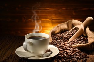 Cup of coffee with smoke and coffee beans on old wooden background