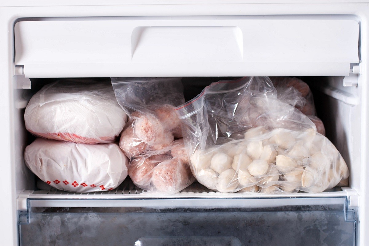 Assortment of frozen meat and dumplings in home fridge. Frozen food in the refrigerator.
