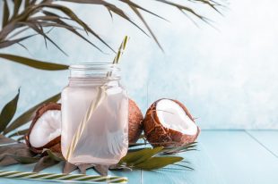 Coconut water and coconuts on a bright pastel background.