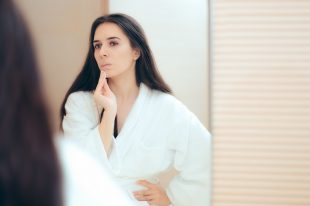 97278234 – woman in bathrobe cleaning her face with make-up remover