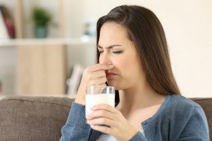 Woman holding a milk glass with bad odor