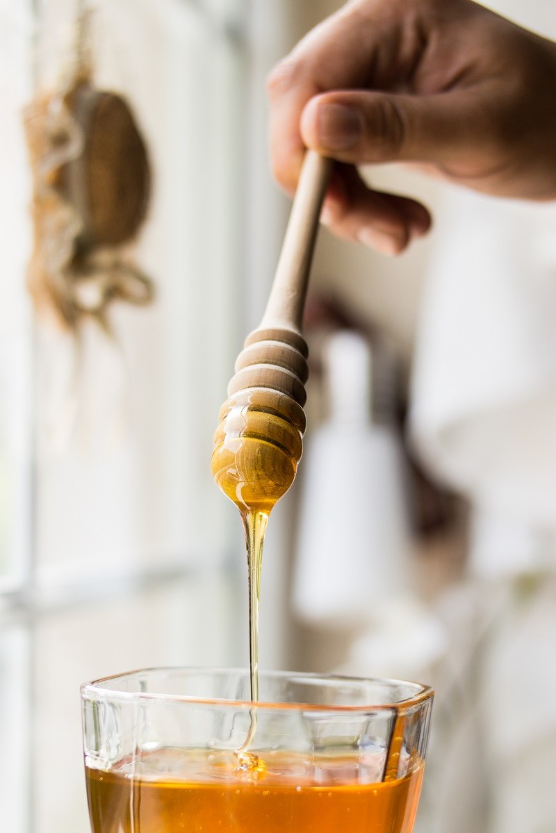 Honey dripping with wooden dipper