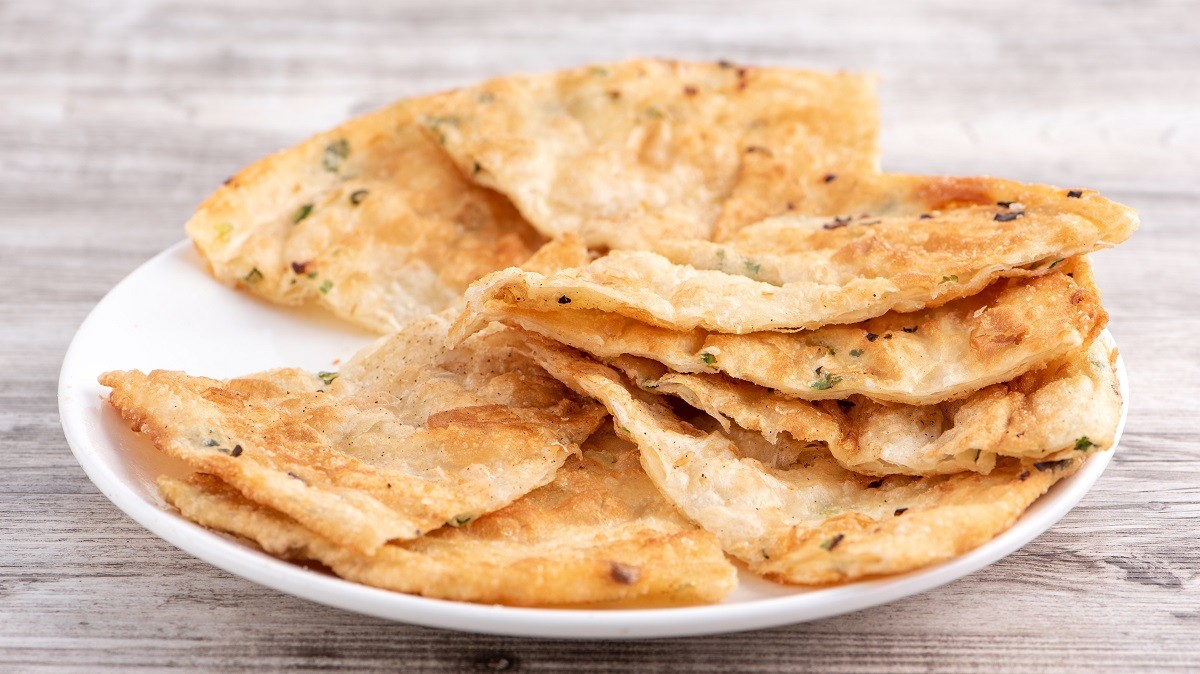 Taiwanese food – delicious flaky scallion pie pancakes on bright wooden table background, traditional snack in Taiwan, close up.