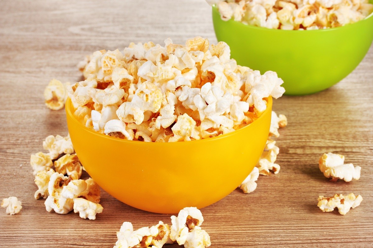 11517561 – popcorn in bright plastic bowls on wooden table