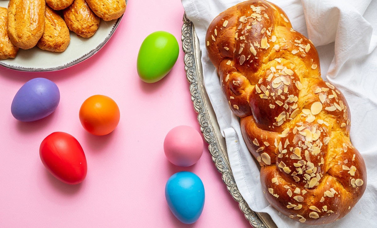 Easter eggs and tsoureki braid, greek easter sweet bread, on pink color background