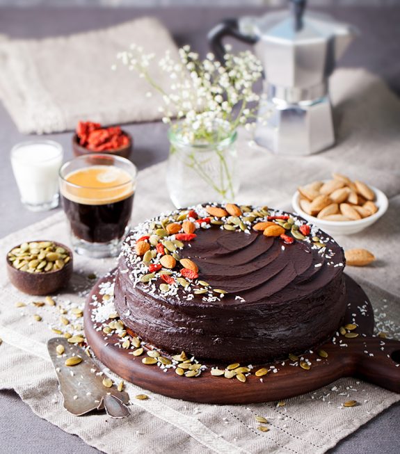 Vegan chocolate beet cake with avocado frosting, decorated with nuts and seeds. Copy space