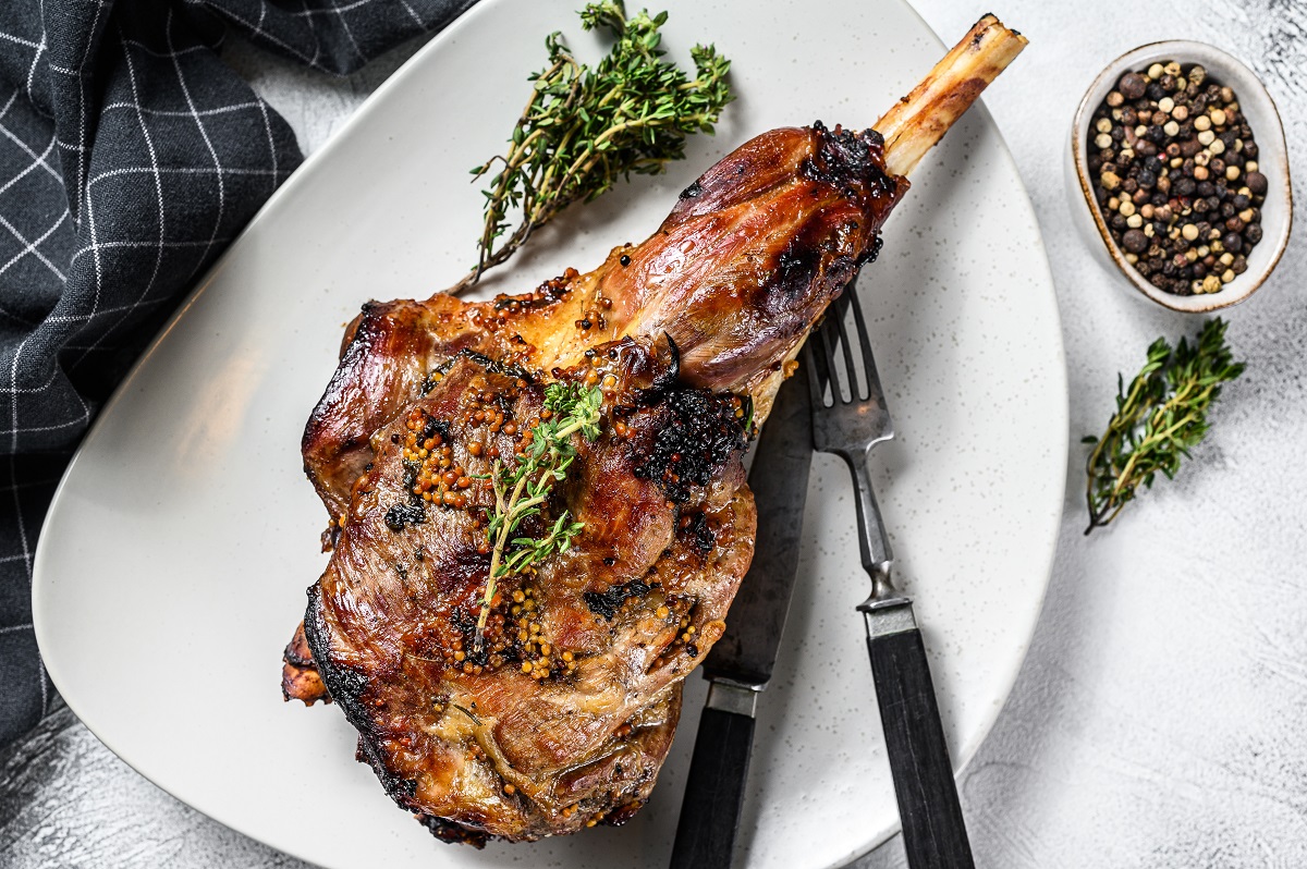 BBQ lamb leg with herbs. Gray background. Top view