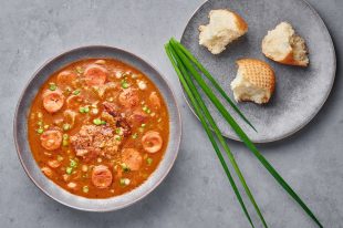 Chicken and Sausage Gumbo soup in gray bowl on concrete backdrop. Gumbo is louisiana cajun cuisine soup with roux. American USA Food. Traditional ethnic meal