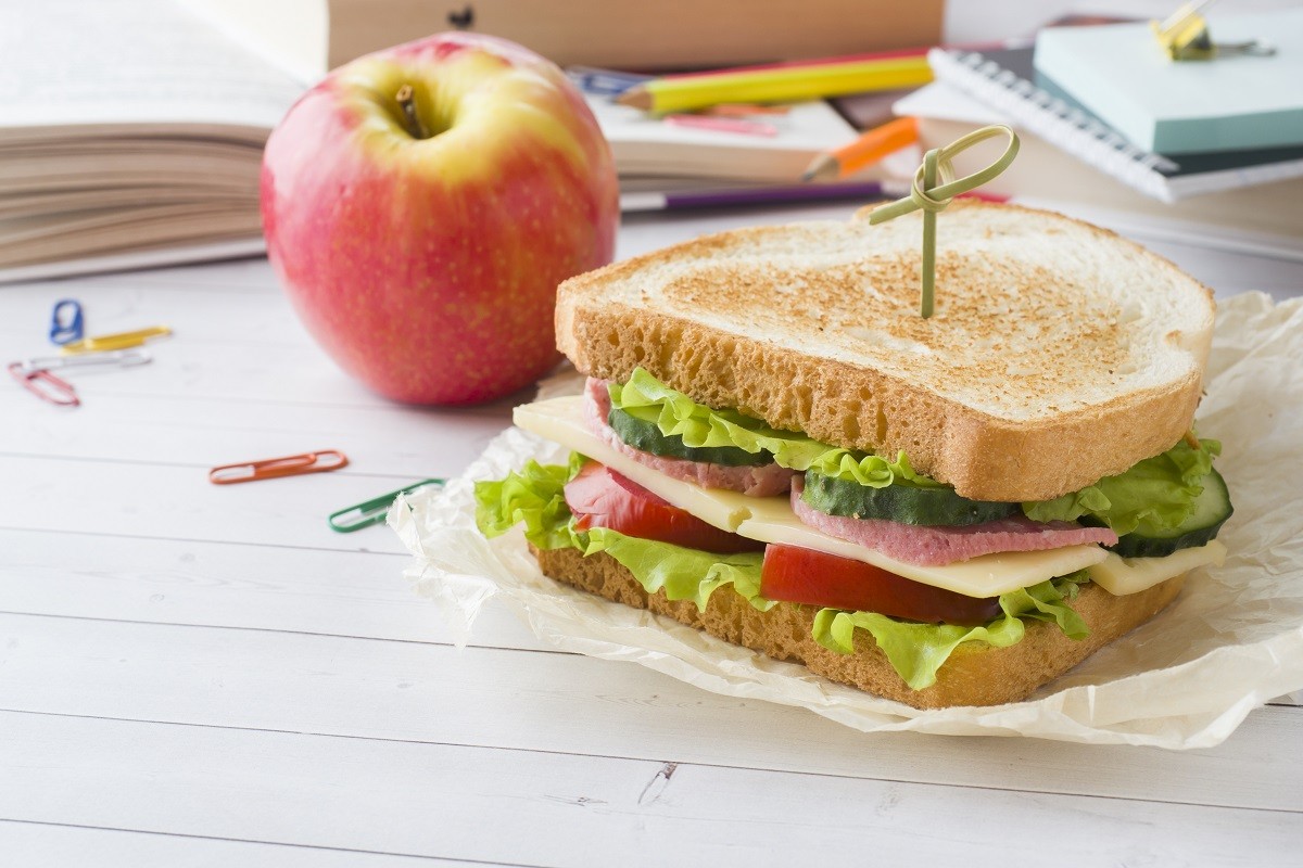 Snack for school with sandwich, fresh Apple and orange juice. Colorful school supplies.