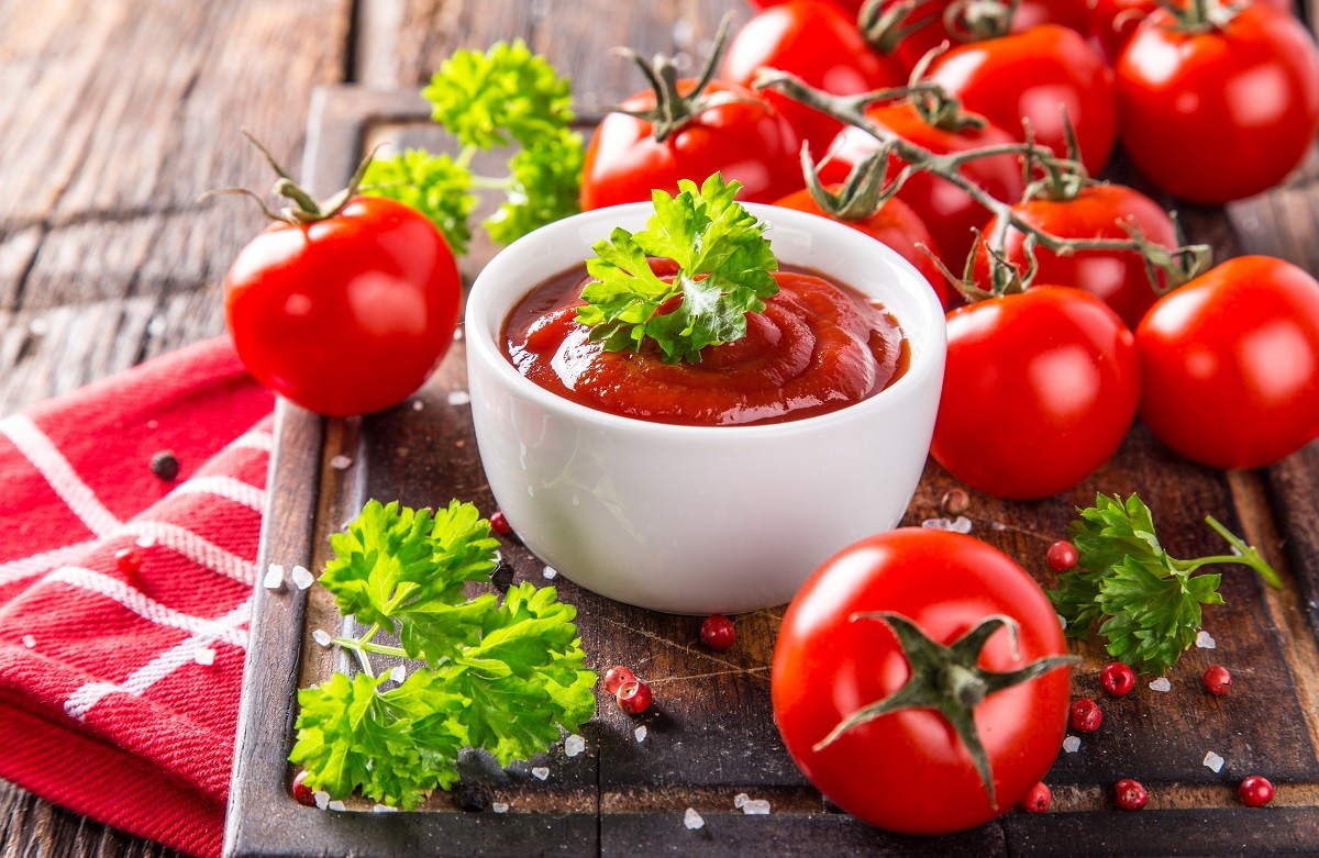 Bowl of tomato sauce and cherry tomatoes on wooden table.