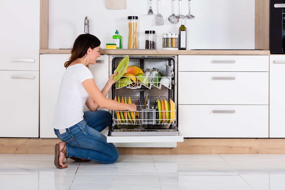 Woman Arranging Plates In Dishwasher