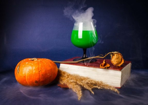 Still life with pumpkin, book, rose and Halloween drinks