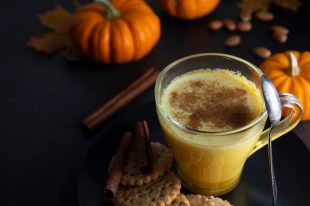 Pumpkin spiced latte macchiato on a dark wooden background autumn drink beverage golden milk