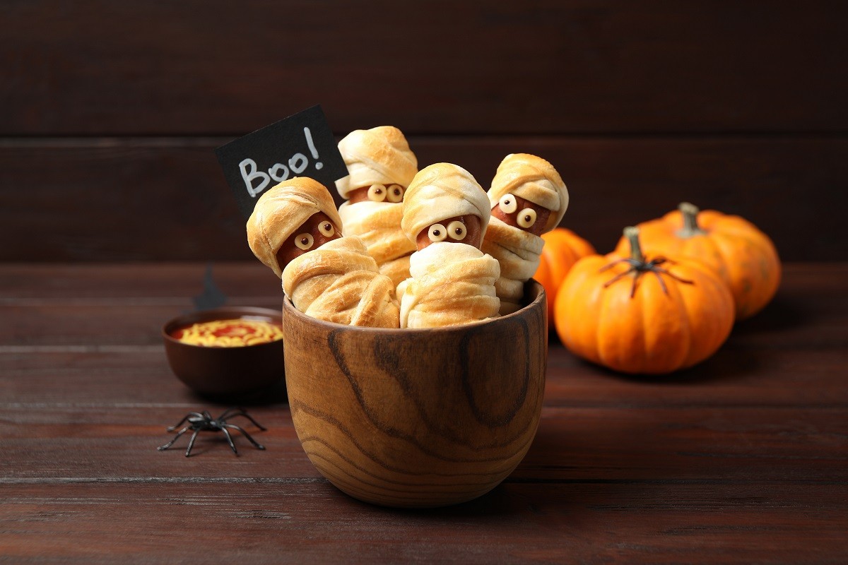 Spooky sausage mummies for Halloween party served on wooden table