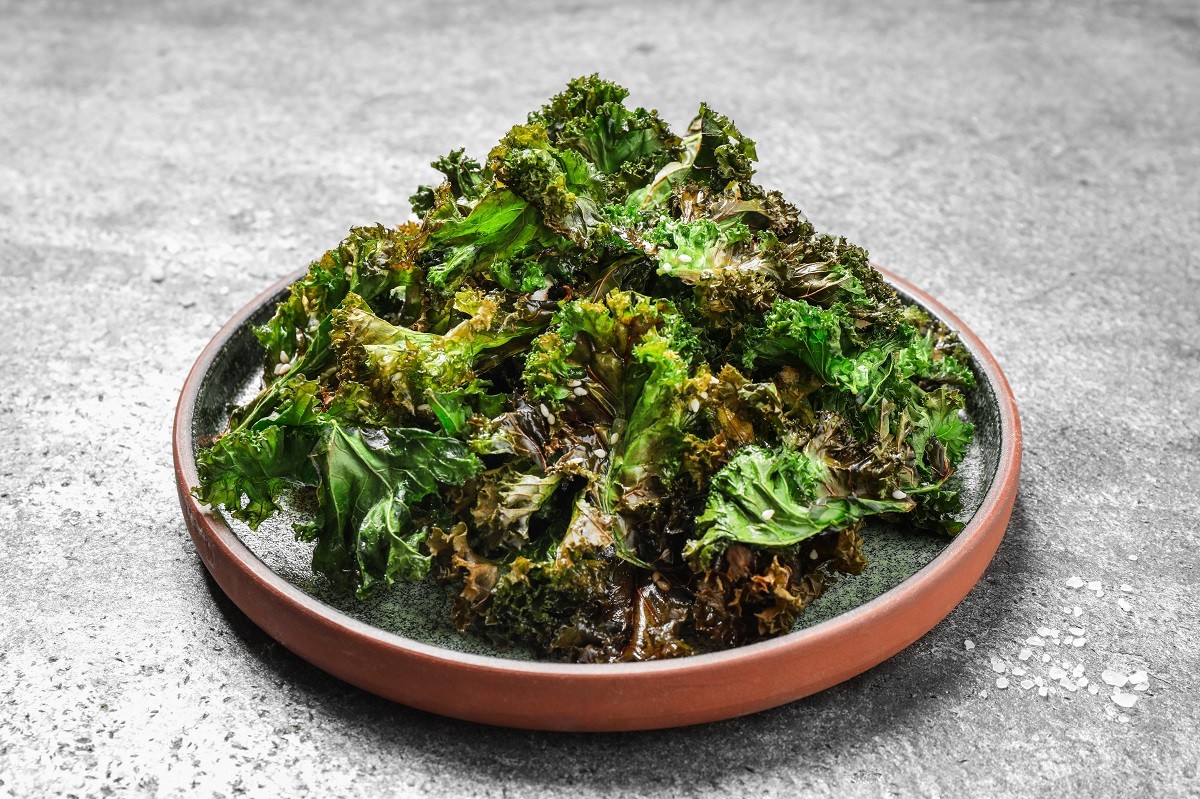 Tasty baked kale chips on grey table