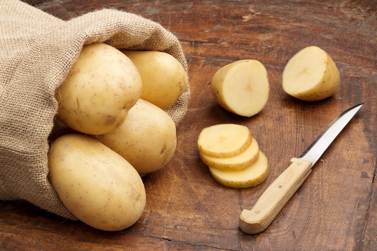 21830440 – raw potatoes and fnife on a wooden background