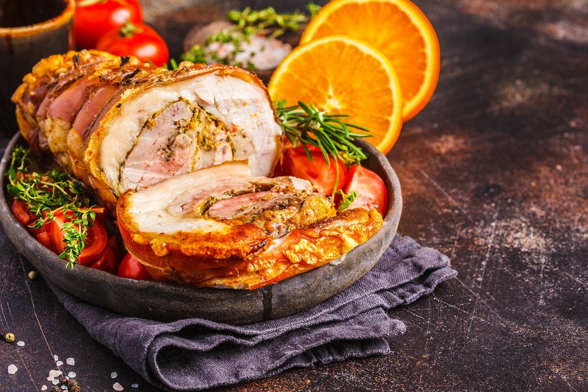 Classic Italian baked porchetta with oranges, copy space. Baked