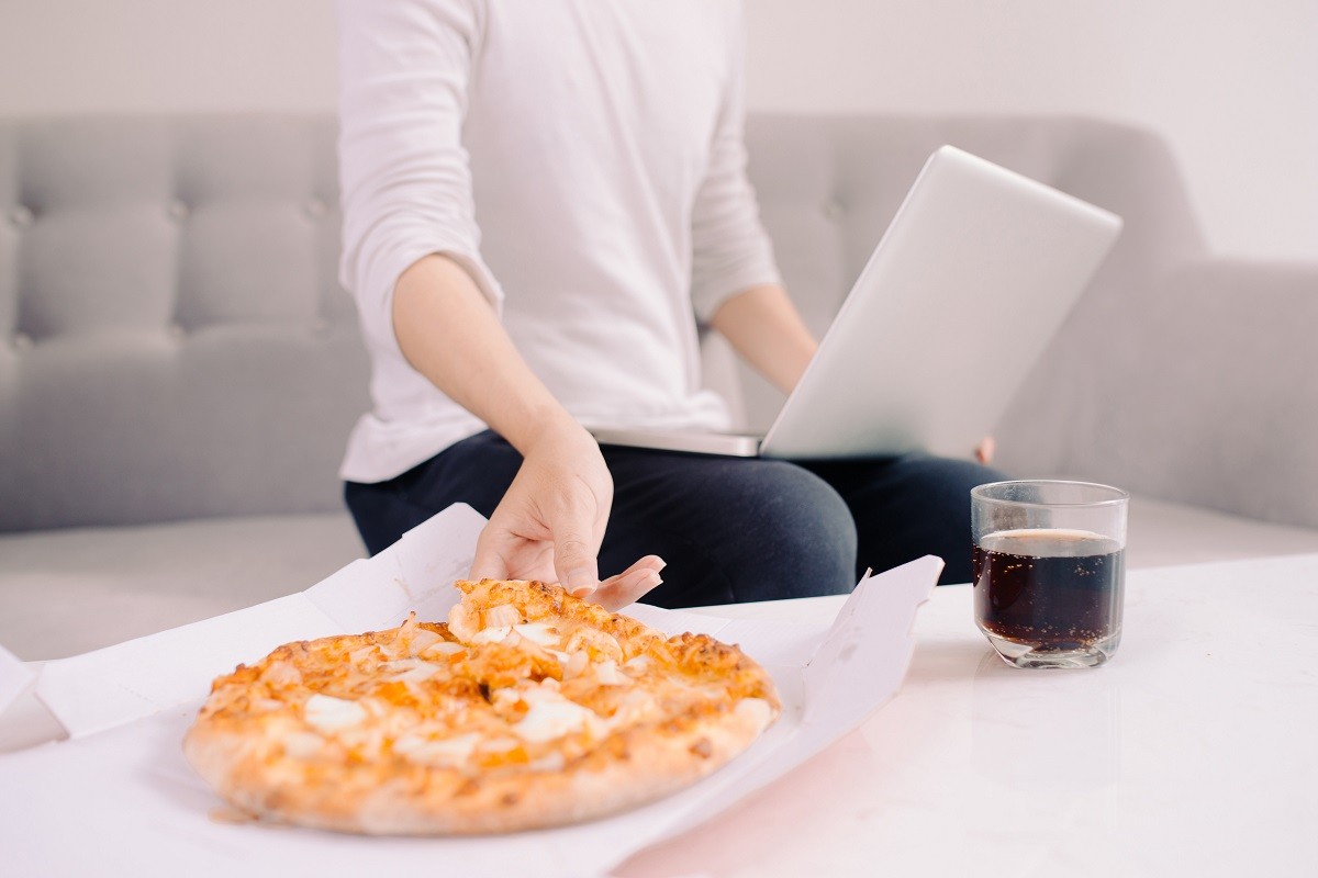 Male freelancer eating pizza while working  at home office