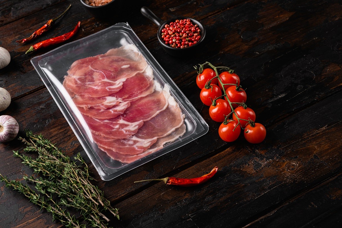 Prosciutto pack, on old dark wooden table background, with copy space for text