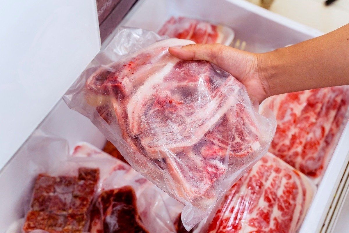 Hand choosing fresh raw ribs meat in freezer