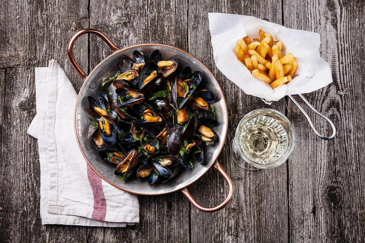 Mussels, french fries and wine on dark wooden background